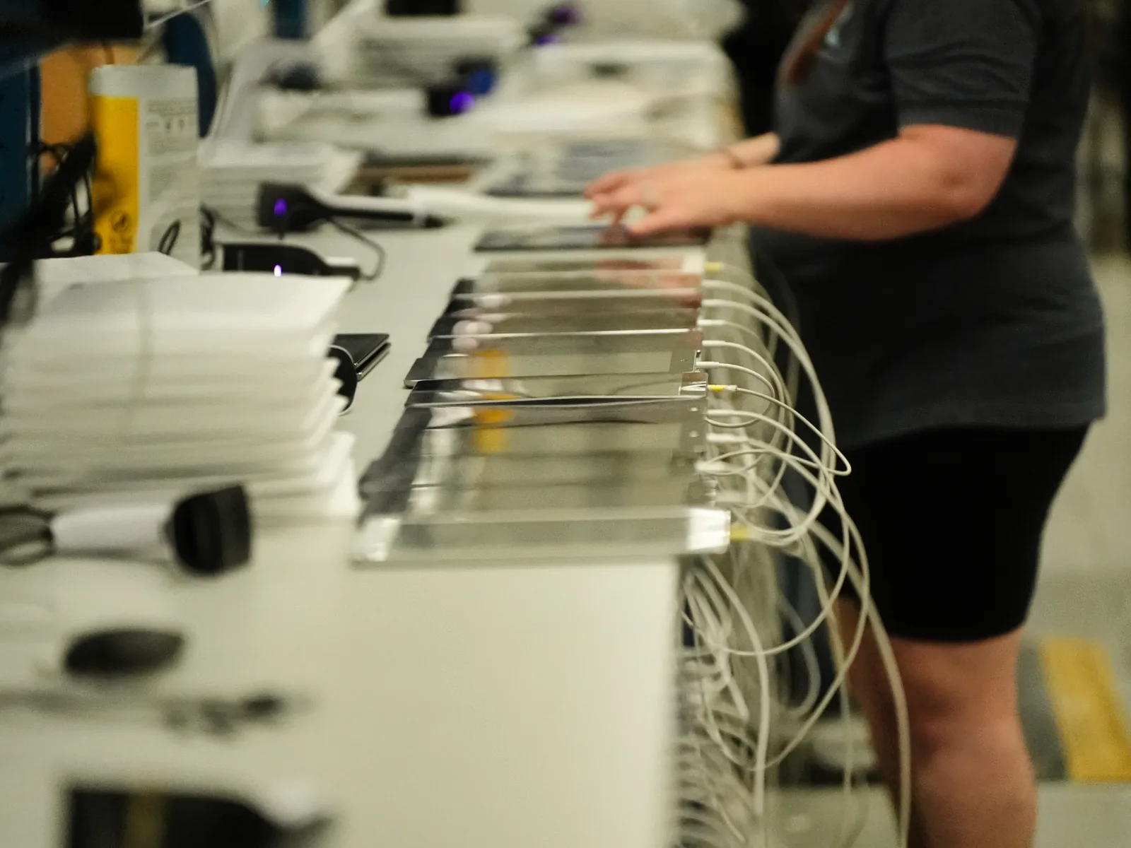 A Refreshed Tech technician works along an inspection bench lined with tablets plugged in for testing at the Ashley, Indiana facility