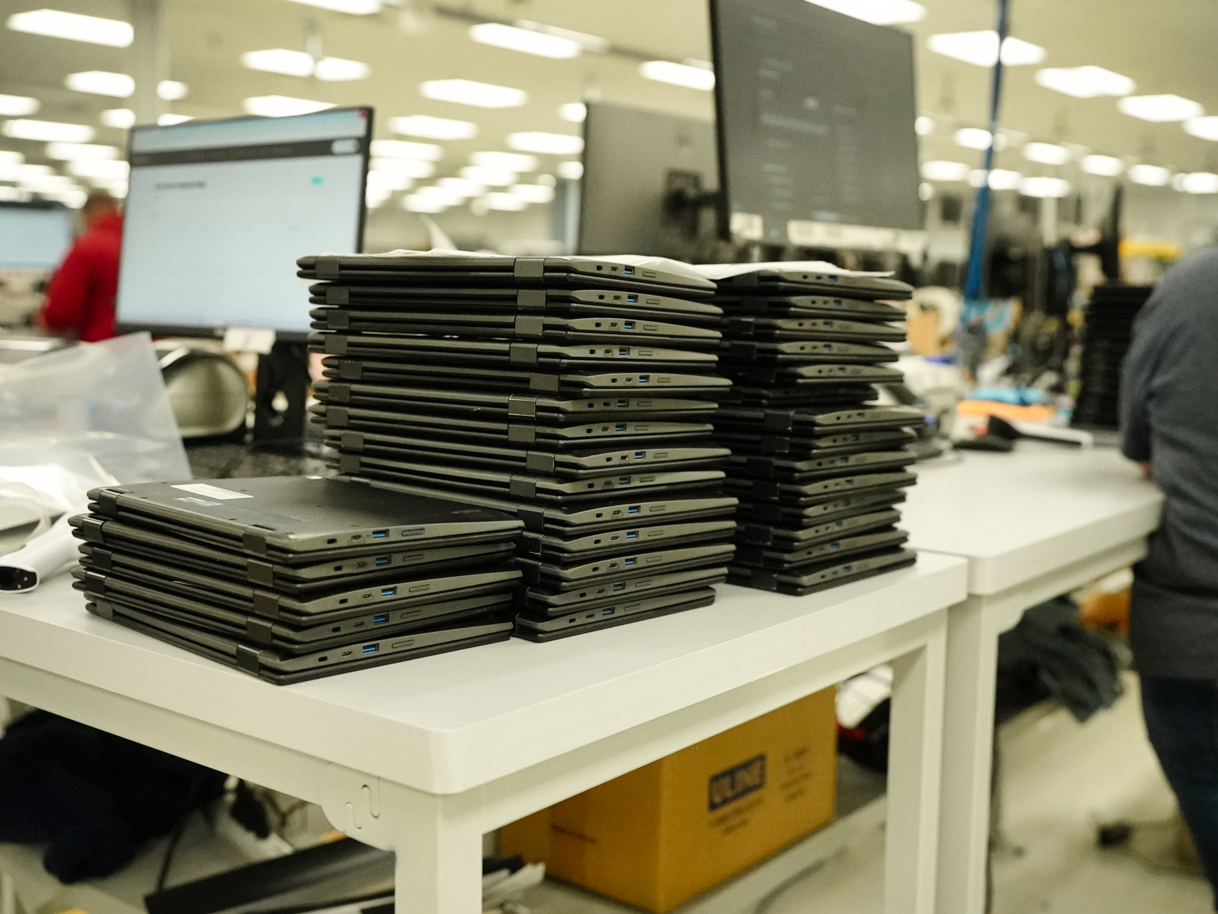 Graded laptops stacked on the processing bench at Refreshed Tech